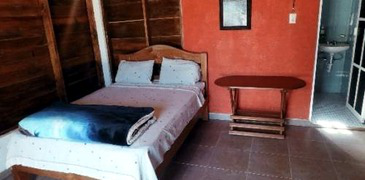 Habitación con pared roja, cama y acceso a baño privado.
