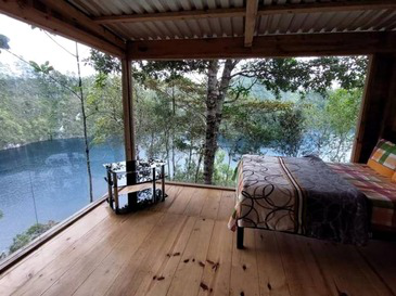 Cama junto a ventanales con vista al lago.