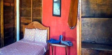 Cama individual en interior de cabaña pequeña.