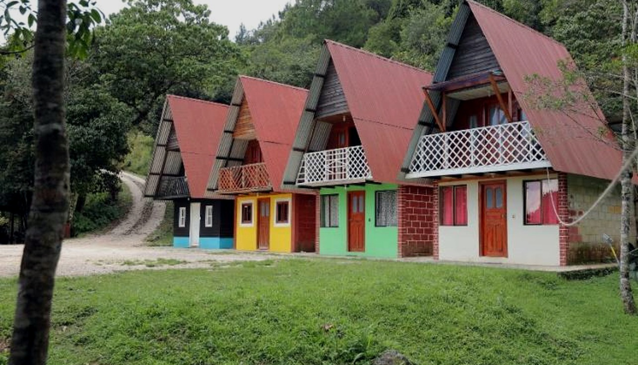 Exterior de cabañas pequeñas tipo A-frame con fachadas de colores.